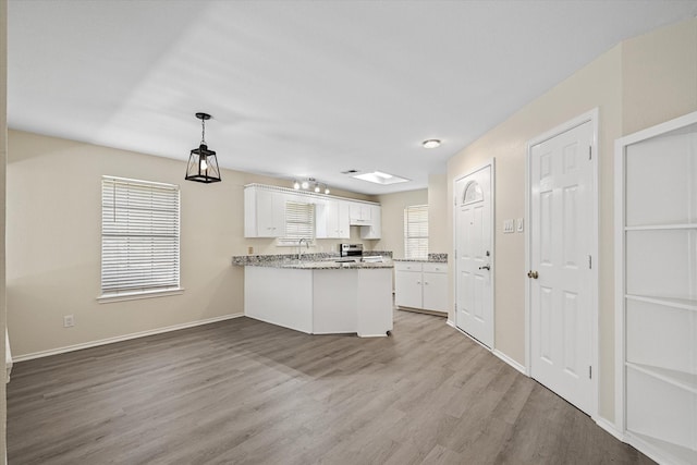 kitchen with electric range, a sink, wood finished floors, a peninsula, and white cabinets