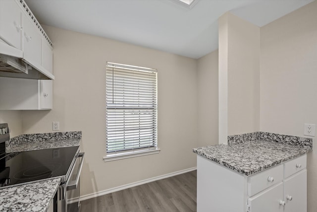 kitchen with light wood-type flooring, baseboards, stainless steel electric stove, and white cabinets