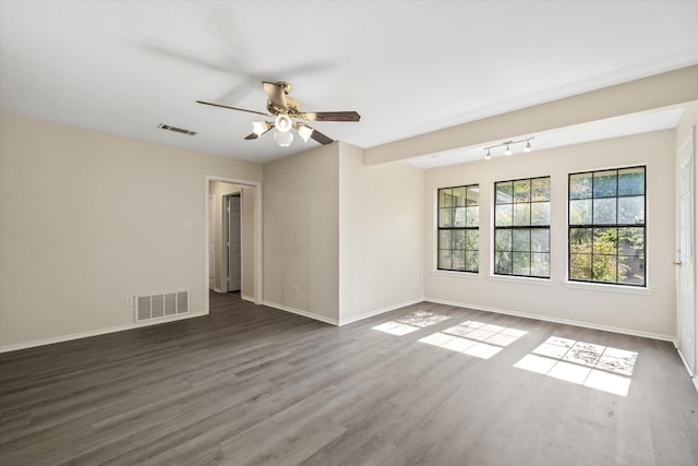 empty room with dark wood finished floors, visible vents, baseboards, and a ceiling fan