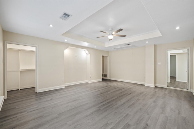 interior space with a raised ceiling, recessed lighting, a ceiling fan, and visible vents