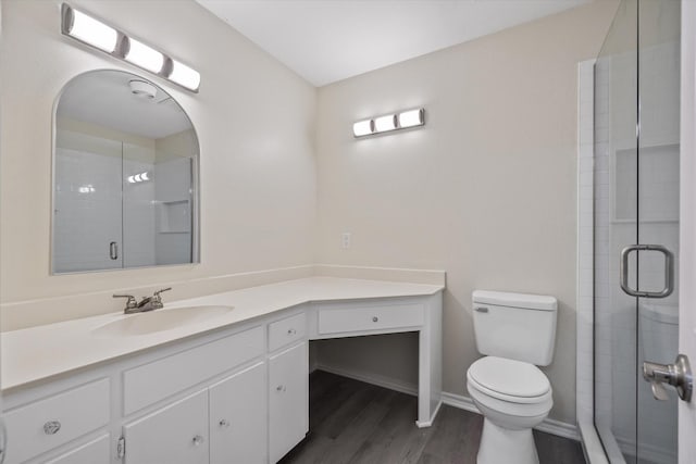 bathroom featuring a stall shower, toilet, wood finished floors, and vanity