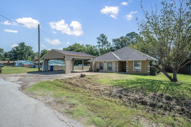 ranch-style house with a front yard, a detached carport, driveway, and fence