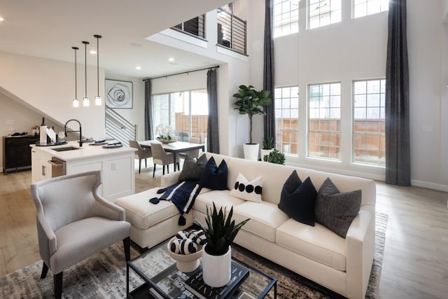 living room featuring a high ceiling, recessed lighting, and light wood-type flooring