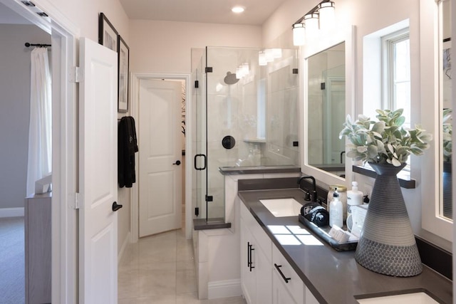 bathroom with a shower stall, double vanity, and a sink