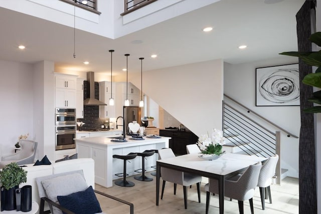 dining room featuring recessed lighting, stairway, a towering ceiling, and light wood finished floors