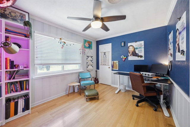 office area featuring a ceiling fan, wood finished floors, a wainscoted wall, and ornamental molding