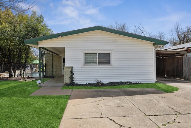 view of front of home featuring an attached carport, driveway, a front yard, and fence