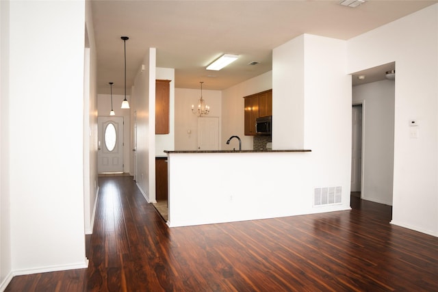 kitchen featuring dark countertops, visible vents, stainless steel microwave, dark wood finished floors, and a sink