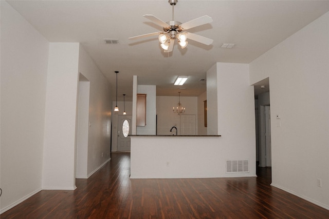 unfurnished living room with a sink, visible vents, dark wood finished floors, and ceiling fan with notable chandelier