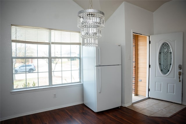 entryway featuring dark wood finished floors, a chandelier, baseboards, and lofted ceiling