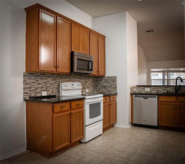 kitchen featuring backsplash, brown cabinets, stainless steel appliances, and a sink