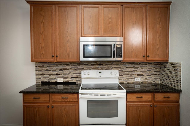 kitchen with dark stone counters, decorative backsplash, electric stove, stainless steel microwave, and brown cabinets