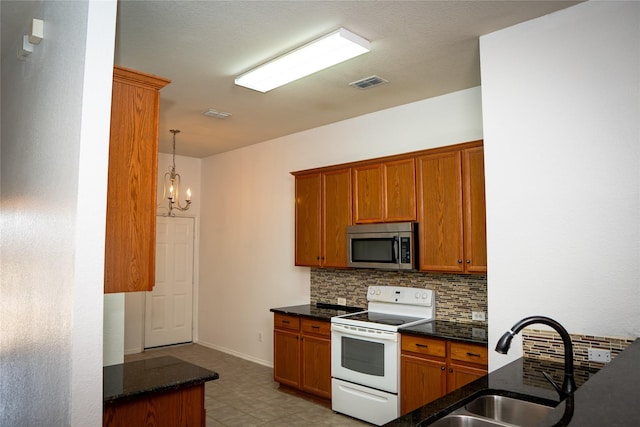 kitchen featuring stainless steel microwave, backsplash, visible vents, white range with electric cooktop, and a sink