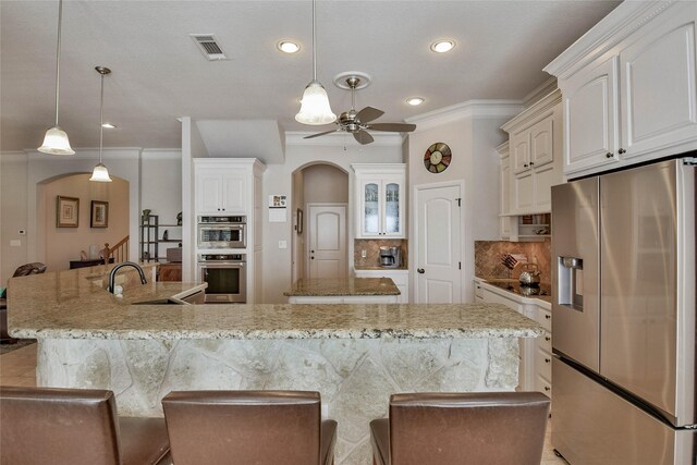 kitchen featuring visible vents, a sink, arched walkways, appliances with stainless steel finishes, and ceiling fan