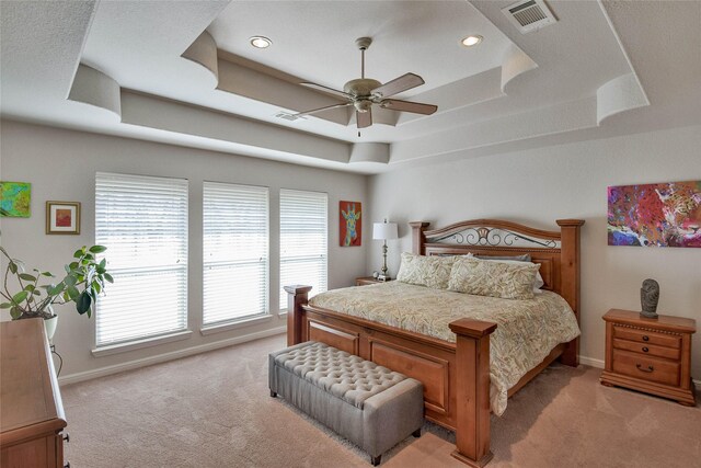 bedroom featuring visible vents, a raised ceiling, and light carpet