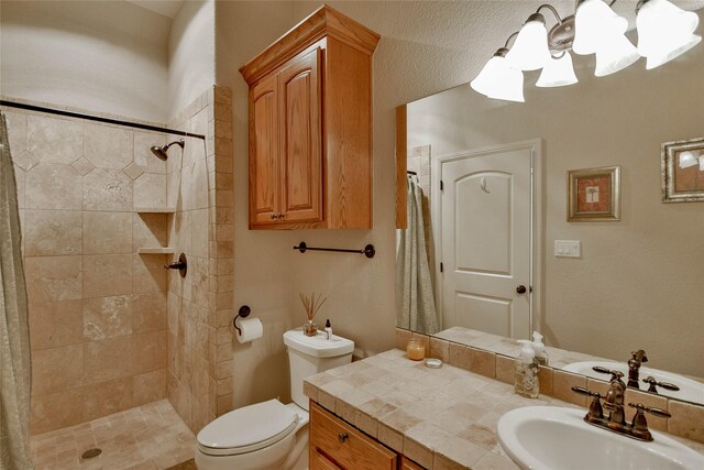 full bathroom featuring vanity, a notable chandelier, toilet, and a tile shower