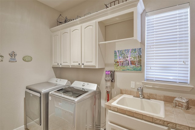 clothes washing area with washing machine and dryer, cabinet space, and a sink