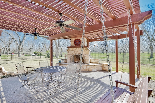 view of patio featuring outdoor dining space, fence, and an outdoor stone fireplace