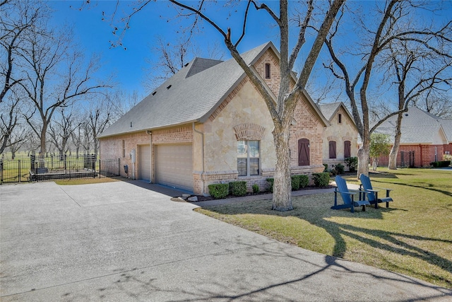 view of front facade with fence, an attached garage, concrete driveway, a front lawn, and stone siding