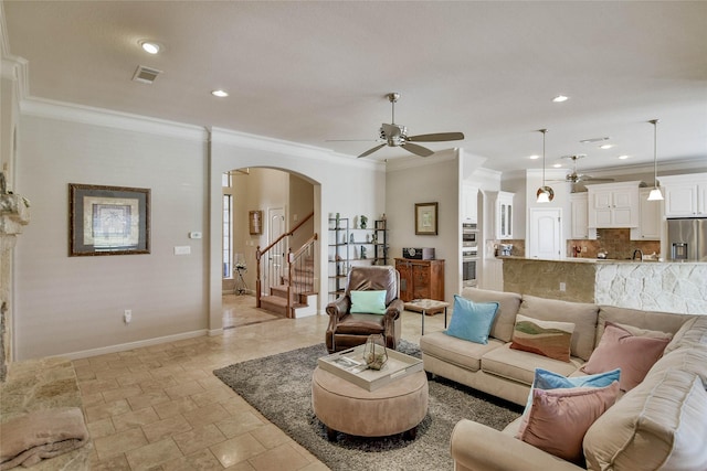 living room with crown molding, baseboards, arched walkways, and ceiling fan