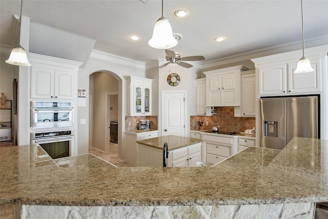 kitchen featuring backsplash, arched walkways, white cabinets, stainless steel appliances, and a ceiling fan