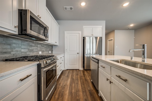 kitchen featuring visible vents, a sink, backsplash, stainless steel appliances, and dark wood-style flooring