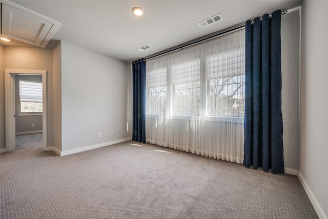 spare room featuring visible vents, baseboards, attic access, and carpet flooring