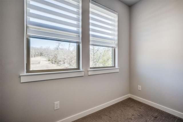 empty room featuring baseboards and dark colored carpet