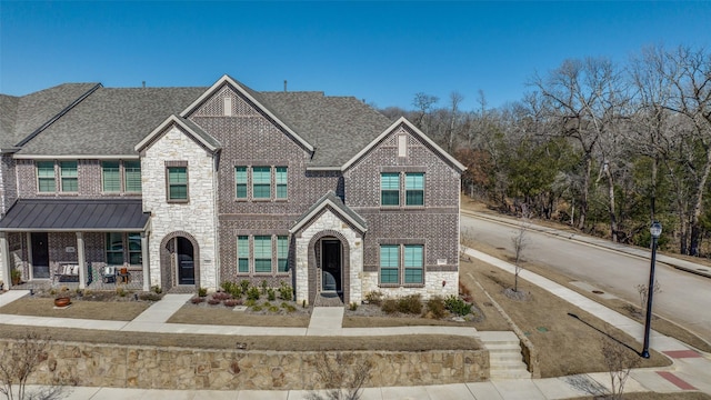 townhome / multi-family property featuring a standing seam roof, brick siding, stone siding, and a shingled roof