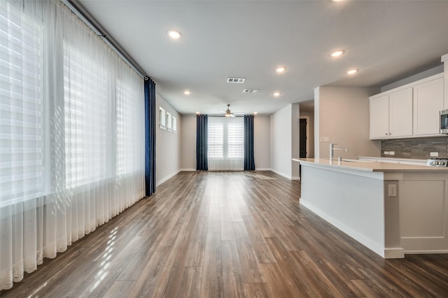 kitchen with recessed lighting, dark wood-type flooring, white cabinets, light countertops, and tasteful backsplash