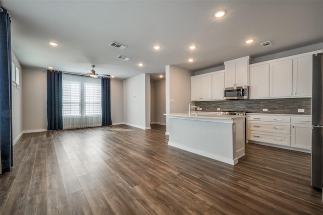 kitchen featuring dark wood finished floors, visible vents, backsplash, and stainless steel appliances