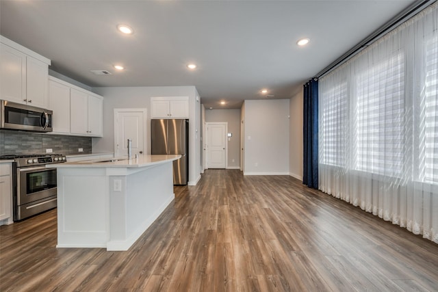 kitchen featuring visible vents, backsplash, a sink, stainless steel appliances, and dark wood-style flooring