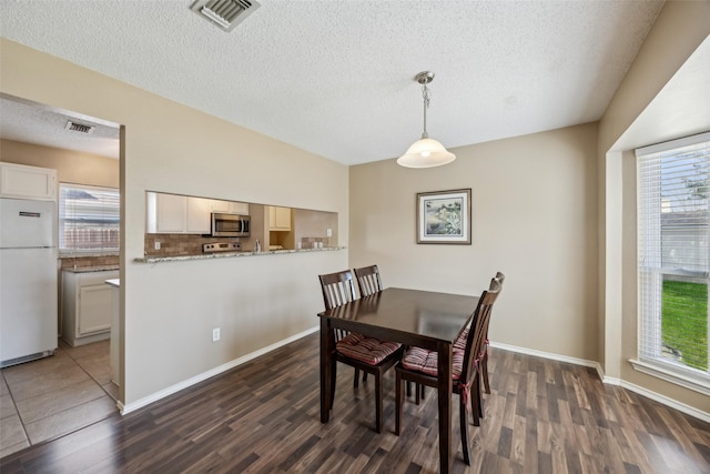 dining room featuring visible vents, a textured ceiling, and dark wood-style flooring