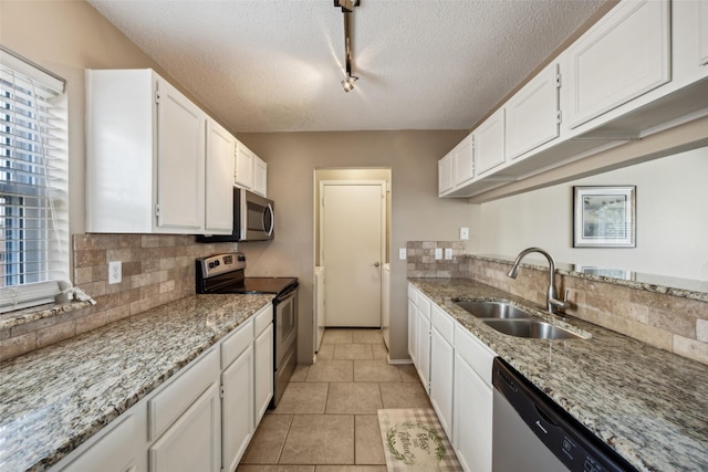 kitchen featuring a sink, white cabinetry, appliances with stainless steel finishes, decorative backsplash, and light stone countertops