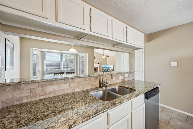 kitchen with a sink, light stone counters, white cabinetry, light tile patterned floors, and dishwasher