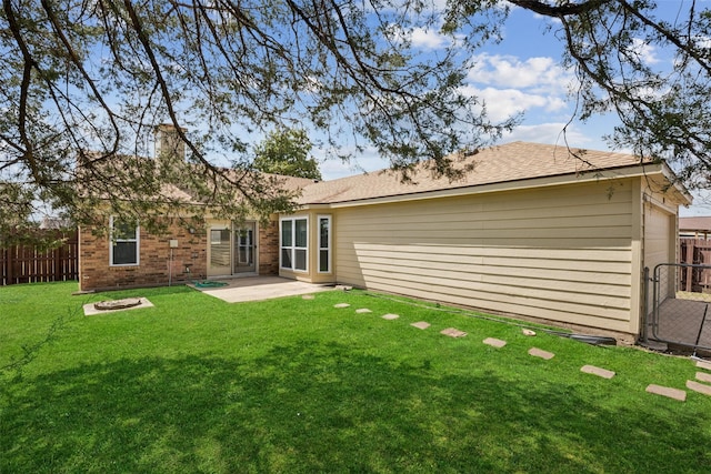 back of property featuring a patio, a yard, a fire pit, brick siding, and fence private yard