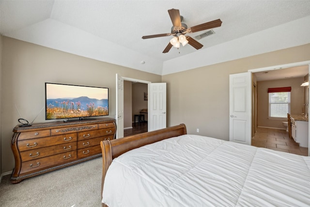 bedroom featuring a ceiling fan, visible vents, baseboards, lofted ceiling, and ensuite bathroom