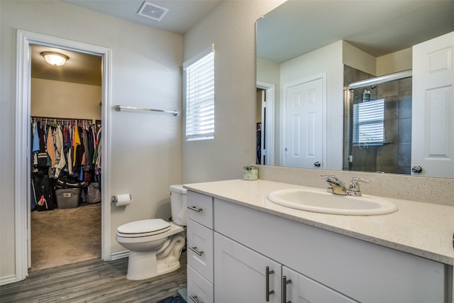 bathroom featuring visible vents, toilet, a stall shower, wood finished floors, and vanity