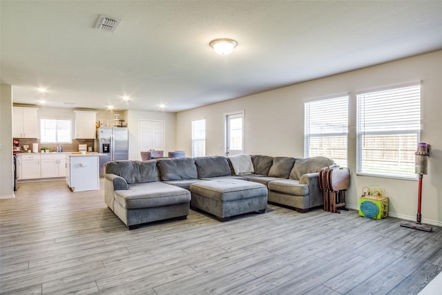 living area with visible vents, baseboards, and light wood finished floors