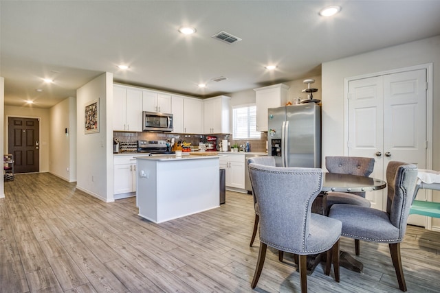 kitchen featuring visible vents, backsplash, appliances with stainless steel finishes, white cabinets, and light wood finished floors