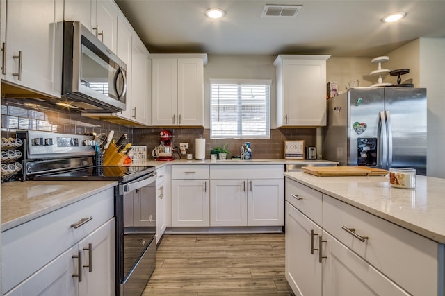 kitchen with visible vents, a sink, tasteful backsplash, white cabinetry, and appliances with stainless steel finishes