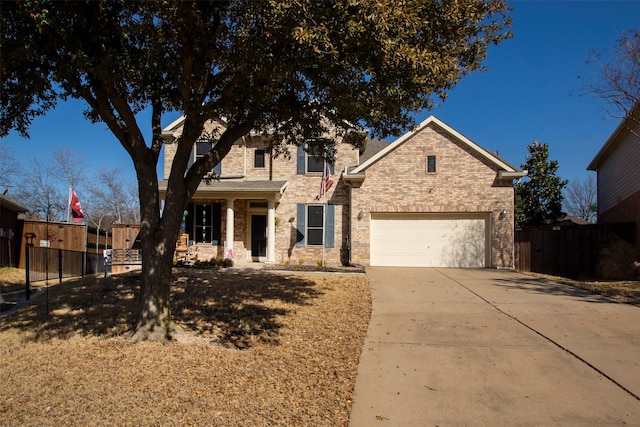 traditional-style home with fence, brick siding, and driveway