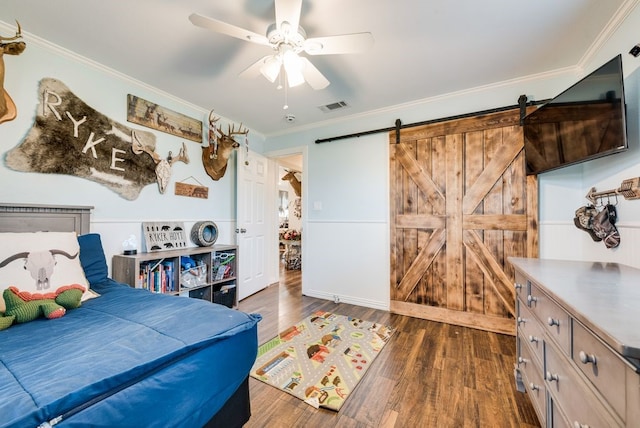 bedroom with visible vents, crown molding, a barn door, dark wood-style floors, and a ceiling fan