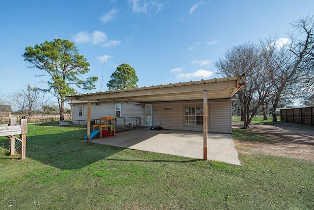 rear view of house with an attached carport, fence, metal roof, a yard, and a patio area