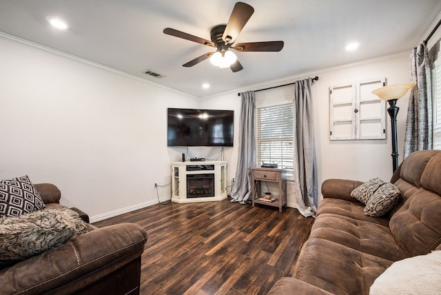 living room with wood finished floors, visible vents, a fireplace, ceiling fan, and crown molding