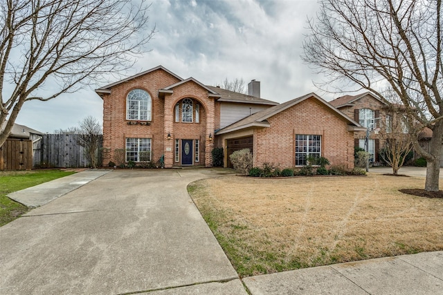 traditional-style home with driveway, a front lawn, a garage, brick siding, and a chimney