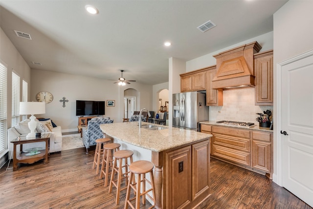 kitchen featuring visible vents, custom range hood, a sink, arched walkways, and appliances with stainless steel finishes