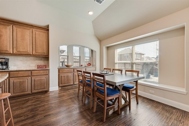 dining area featuring lofted ceiling, a healthy amount of sunlight, and dark wood-style flooring