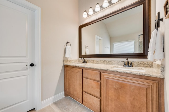 bathroom with tile patterned flooring, double vanity, baseboards, and a sink