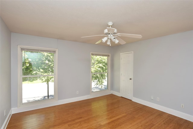 unfurnished room with light wood-style flooring, a ceiling fan, and baseboards